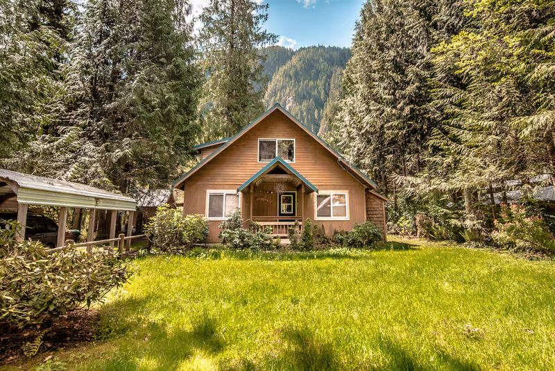 Front of the cedar chalet with a green lawn and forest behind